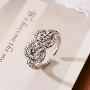Silver twisted knot open ring with cubic zirconia on open book background