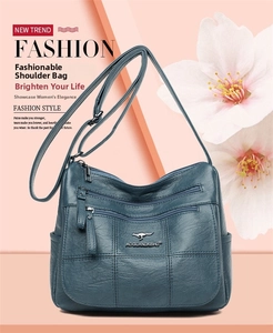 Detail of dark peacock green crossbody bag with multi-zipper pockets and litchi texture