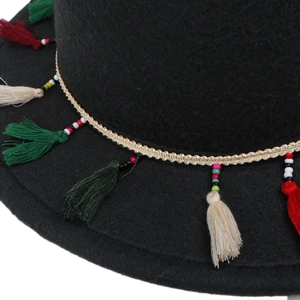Détail d'une bande tissée bohème avec pompons colorés et perles sur chapeau noir