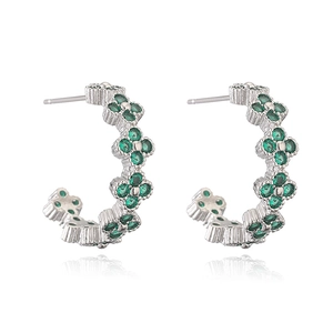 Detail of silver clover C-shaped hoop earrings with green zircon stones on white base