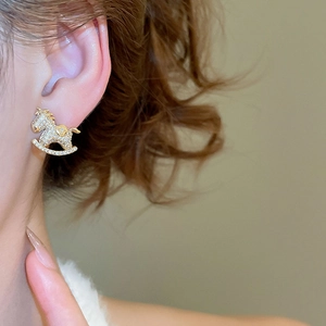 Close-up of a rocking horse stud earring with sparkling zircons worn on the ear