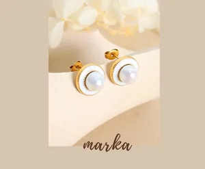 Detail of vintage gold stud earrings with white enamel and iridescent pearl on display