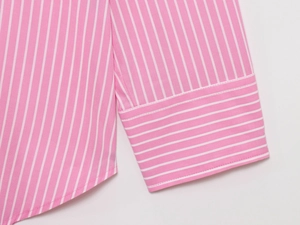 Close-up detail of pink and white striped shirt cuffs with fine stitching on white fabric