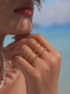 Macro detail of four stacked 18k gold plated geometric square rings on a model finger