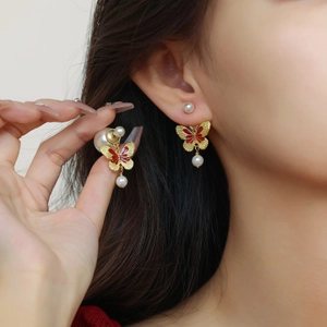 Détails des boucles d'oreilles papillon dorées avec émail rouge et perles blanches
