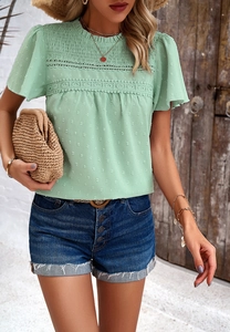 Detail of light green short sleeve top featuring elegant lace trim and textured fabric