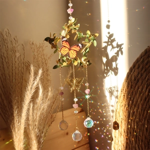 Detail of star metal suncatcher with green leaves, butterfly, and crystal prism ball