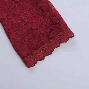 Close-up of burgundy lace texture and delicate embroidery edges on the dress sleeve