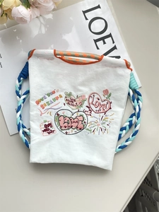 Détail du sac en tissu oxford blanc avec broderies colorées et poignées en corde tressée
