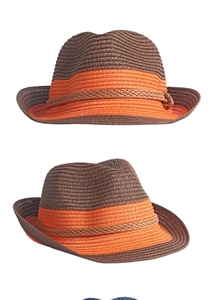 Detail view of foldable straw fedora with brown crown, orange brim and woven texture