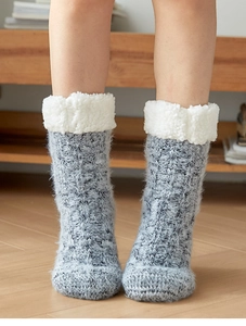 Thick knit slipper socks with soft fleece lining shown on wooden floor for home comfort
