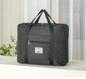 Close-up of a black travel bag with a durable zipper pocket and decorative white label