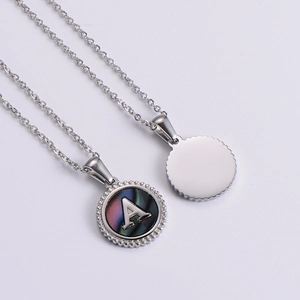 Detail view of silver stainless steel round pendant with letter A and iridescent shell inlay