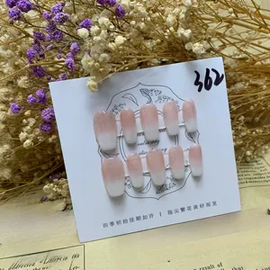 Close-up of pink and white gradient press-on nails displayed on an elegant floral card