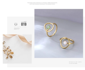 Detalle de dos anillos geométricos dorados con piedra de jade verde y opale blanco