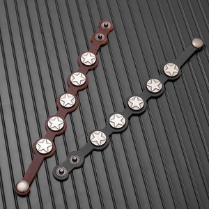 Close-up of black and brown leather bracelets with silver star rivets on textured surface