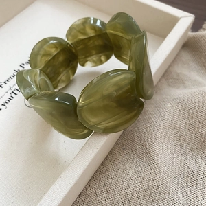 Macro shot of olive green marble texture resin segments on minimalist acrylic bracelet