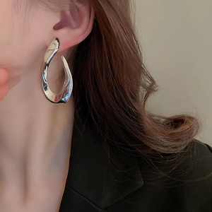 Close-up of a silver irregular twisted geometric earring on female model with black blazer