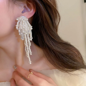 Gros plan de boucles d'oreilles en perles blanches avec de longues franges à franges
