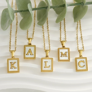 18K gold-plated stainless steel shell initial necklaces on green branch background