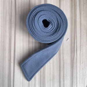 Detail of grey-blue wool coat belt with soft brushed texture on wooden background