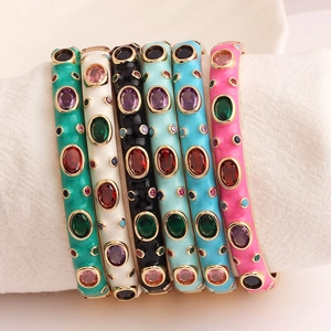 Detail of colorful enamel gold bracelets with multicolored zircon inlays on white roll