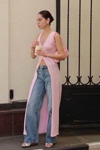 Detail view of light pink long knit vest featuring a deep V-neck and high front slit design