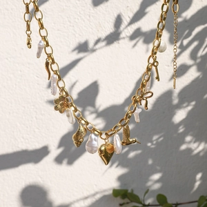 Vue détaillée d'un collier doré orné de perles baroques et de multiples breloques