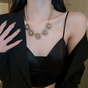 Close-up of vintage flower and pearl necklace set in gold finish worn by a model