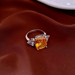 Macro shot of silver ring with luxury yellow cushion cut zircon on brown silk fabric