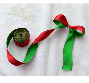 Detail of red and green double-sided satin ribbon with DIY bow on white plush background