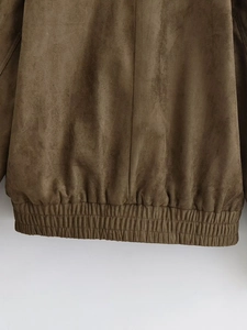 Détail d'une veste en daim beige montrant l'ourlet froncé élastique et la texture