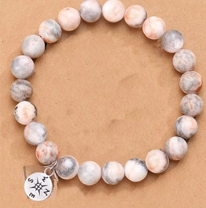Close-up of 8mm pink zebra jasper stone bead bracelet with a compass metal charm