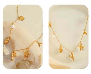 Detail of 18K gold plated necklace featuring sea shell pearls and initial pendants