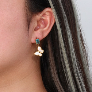 Golden earrings with square blue zircon and white butterfly pendant on model