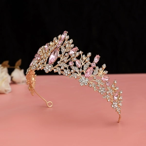 Close-up of golden crown with pink water-drop crystals and intricate leaf carvings