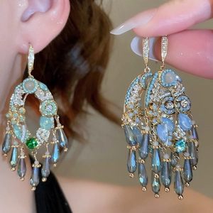 Dettaglio di eleganti orecchini in oro con cristalli di zircone e frange di pietre
