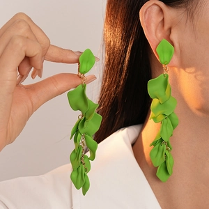 Close-up of green petal drop earrings featuring long gold chain tassels on model
