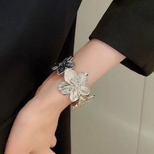 Detail of silver metallic flower cuff bracelet with black enamel and textured petals