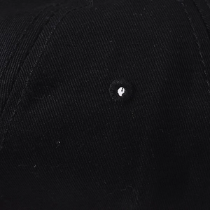 Close-up of embroidered ventilation eyelet on black cotton twill baseball cap