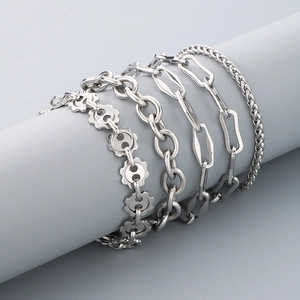 Close-up of five silver-finish stainless steel curb and cable chain bracelets on a display