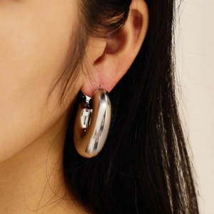 Close-up of thick silver hoop earring with mirror finish on a model showing minimalist style