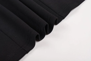 Close-up of black knit fabric texture and double-stitch sewing detail on a hollow dress