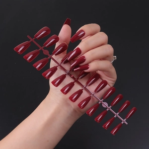 Macro view of long glossy burgundy coffin fake nails set with 24 pieces on dark background