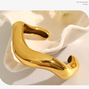 Detailed view of heavy-duty irregular lava texture gold bangle on artistic white tray