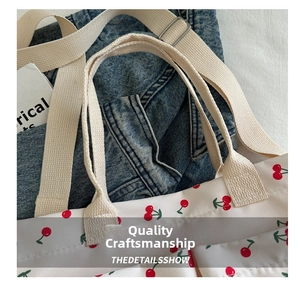 Detail of cherry print canvas tote bag featuring reinforced stitching and webbed straps