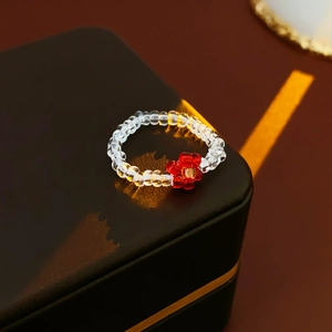 Detailed close-up of handmade beaded flower ring with red petals on a jewelry box
