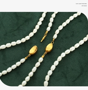 Detail of freshwater pearl necklace with golden clasp on green velvet background