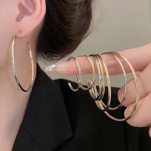 Minimalist glossy round metal hoop earrings in gold and silver set on model