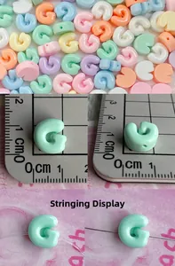 Detailed view of colorful 10mm resin letter G beads with size scale and stringing demo